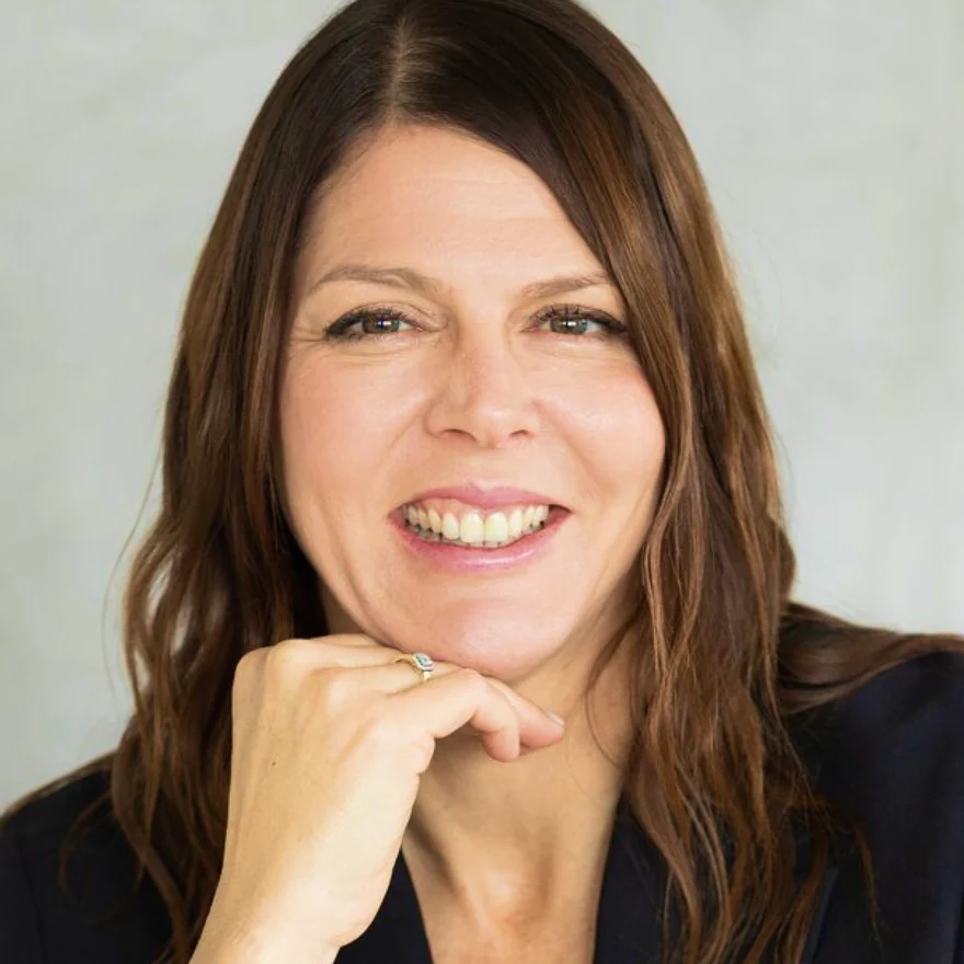 Porträt von Christina Romberger, sie stützt das Kinn auf die Hand und lächelt.